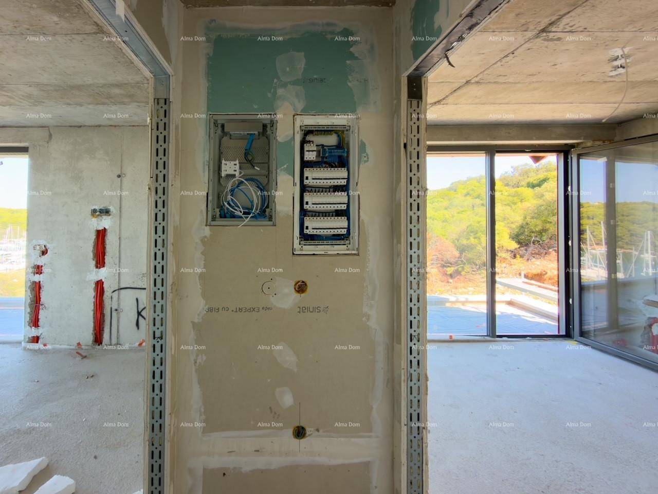 Sichtbare Elektroinstallationen und Schalttafeln in einem unfertigen Innenraum mit Blick ins Grüne.