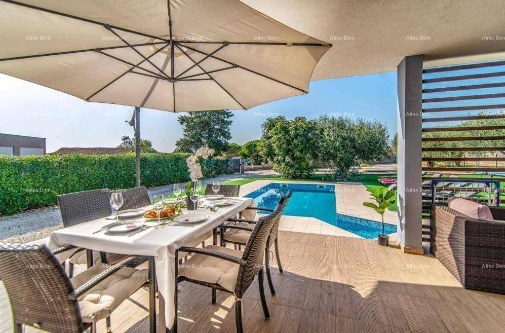 Überdachte Terrasse mit Esstisch und Stühlen, Blick auf den Pool und den Gartenbereich.