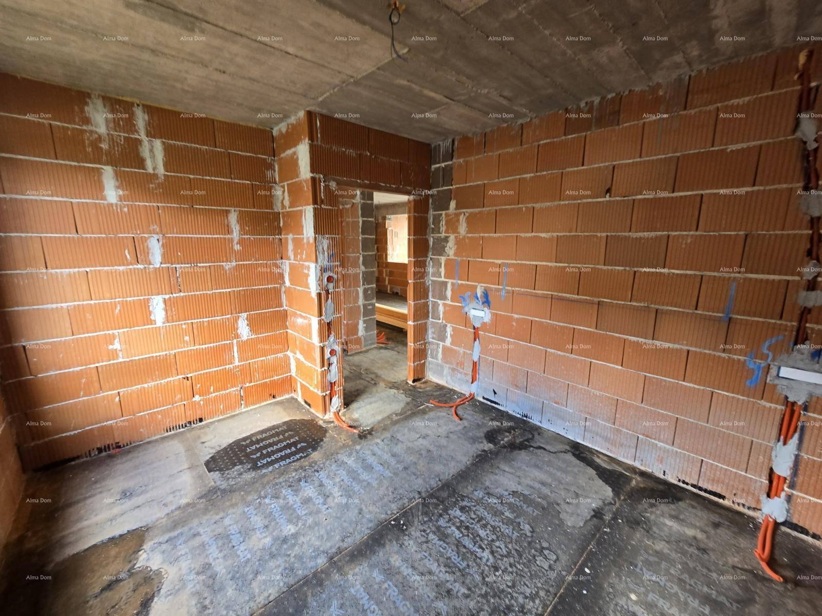 Innenraum im Rohbau mit Ziegelwänden, Türöffnung und vorbereiteten Elektroinstallationen.