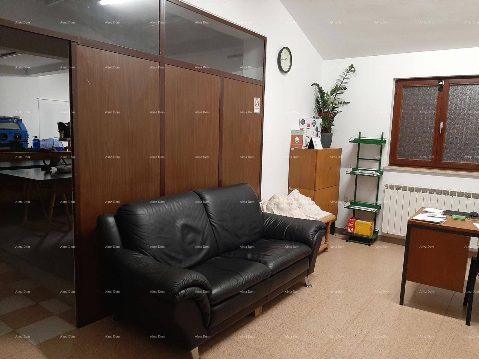 Büroraum mit schwarzem Ledersofa, Teppichboden und Holzabtrennung.