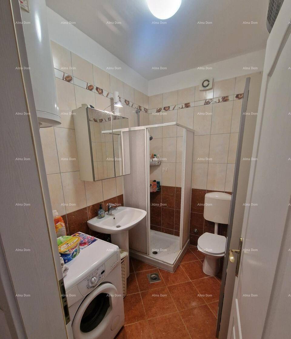 Badezimmer mit Dusche, WC, Waschbecken und Waschmaschine, komplett gefliest.