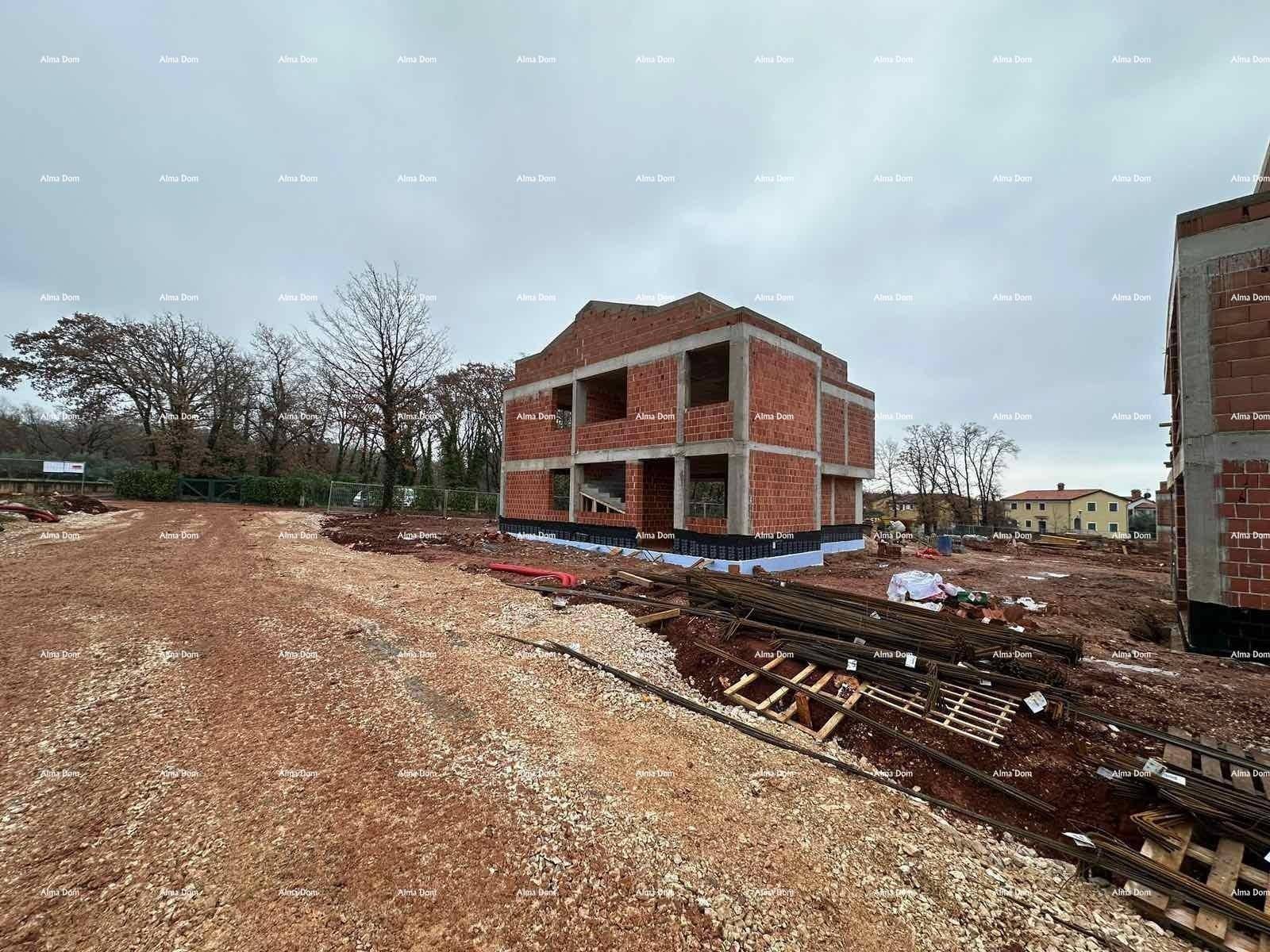 Rohbau eines Hauses mit Ziegelwänden und Betonfundament auf einer Baustelle.