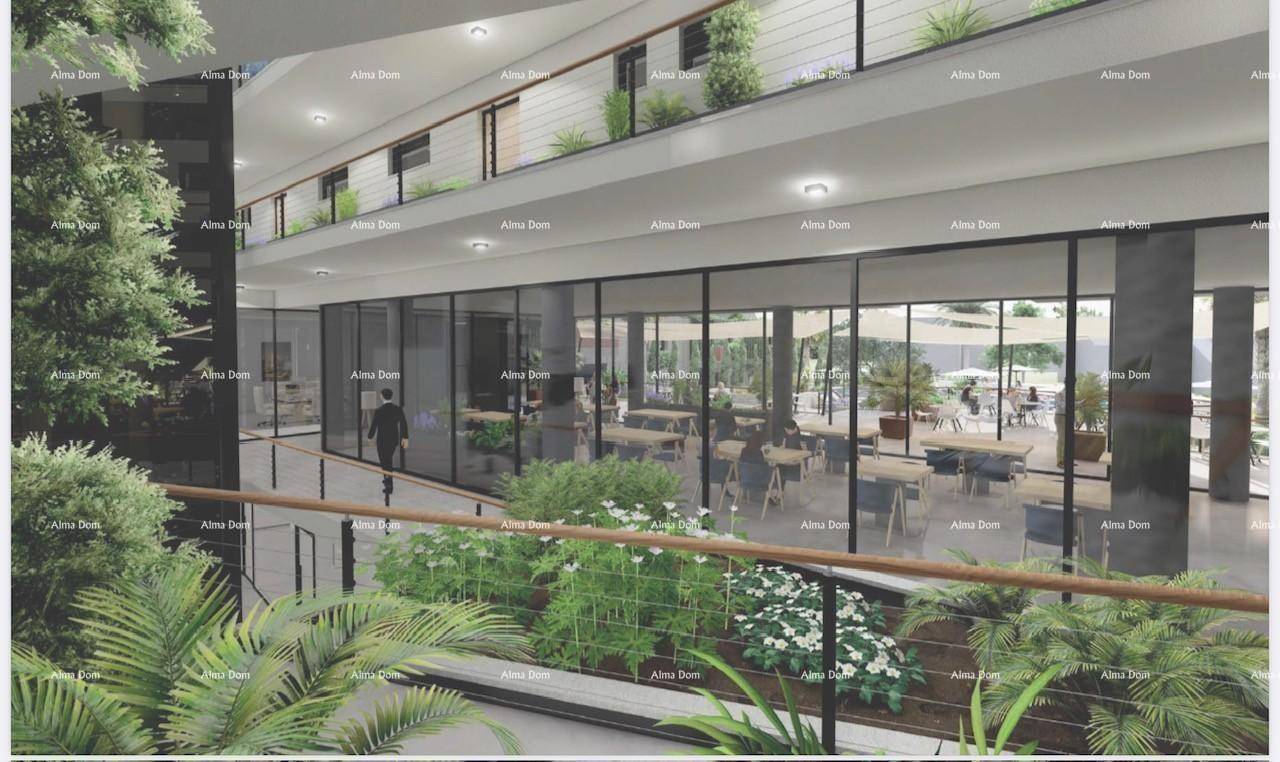 Moderne Lobby mit Glaswänden, üppiger Bepflanzung und Blick auf einen Restaurantbereich.