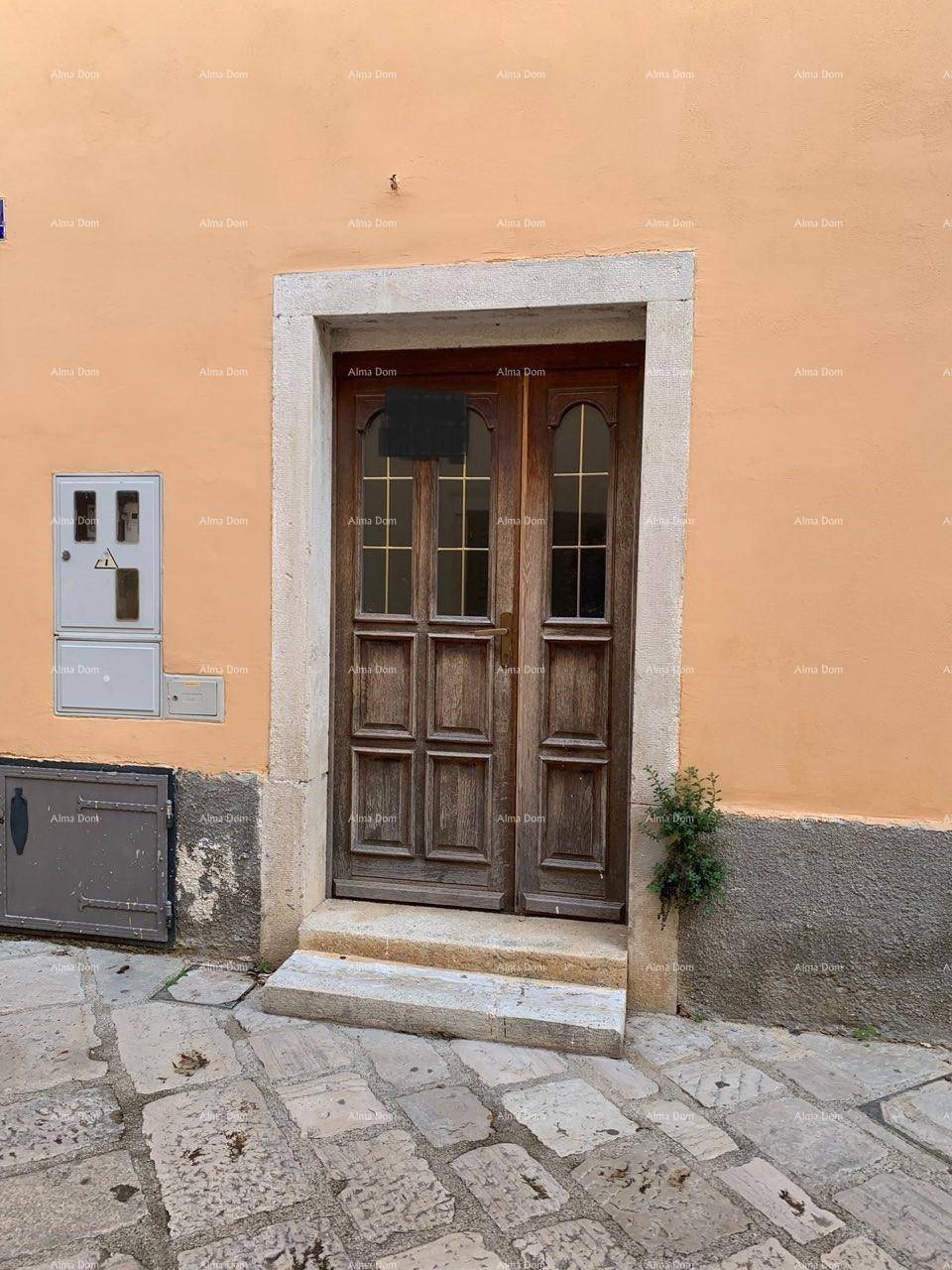 Alter Holzeingang mit Steinstufen und einer Fassade in warmem Orangeton auf Kopfsteinpflaster.