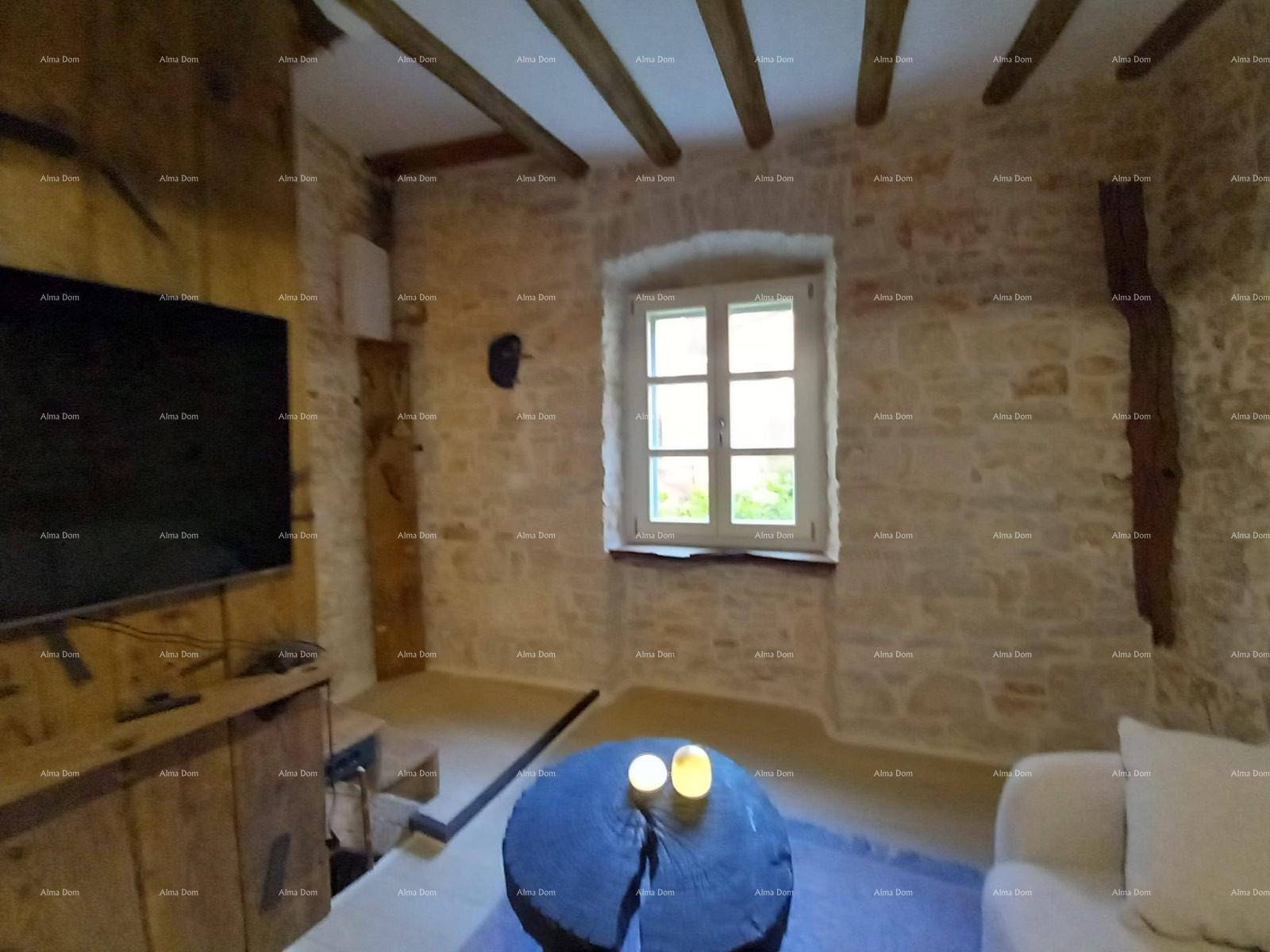 Wohnzimmer mit Steinwänden, Holzbalken und einem kleinen Fenster, das Tageslicht hereinlässt.