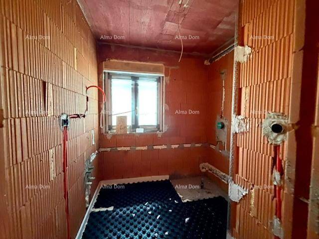 Unfertiges Badezimmer mit Ziegelwänden, Fenster und Vorbereitung für Sanitärinstallationen.