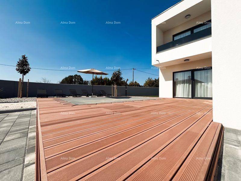 Geräumige Holzterrasse neben dem Haus mit Blick auf den überdachten Poolbereich und den Garten.