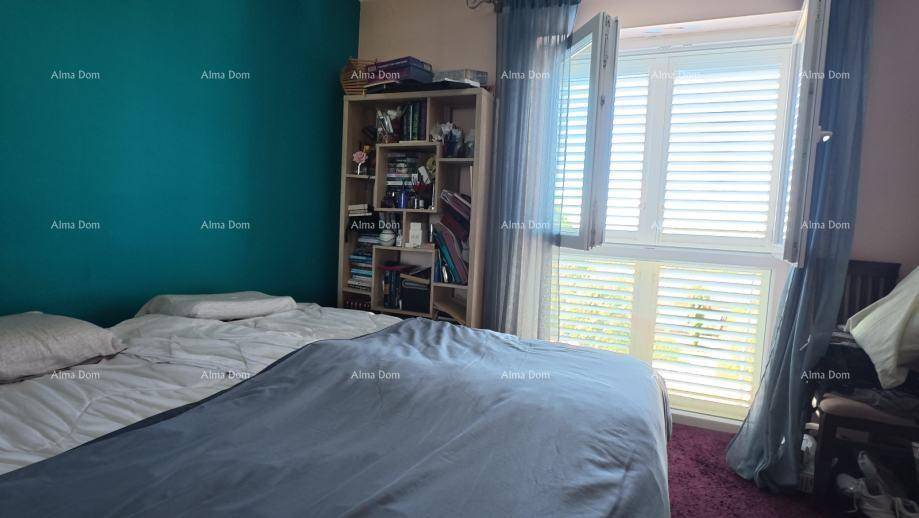 Helles Schlafzimmer mit blaugrüner Wand, Doppelbett und Fenster mit Jalousien.