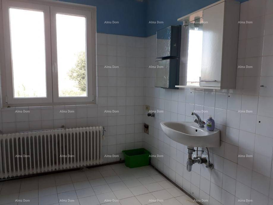 Badezimmer mit Waschbecken, Fenster und Heizkörper, komplett gefliest.