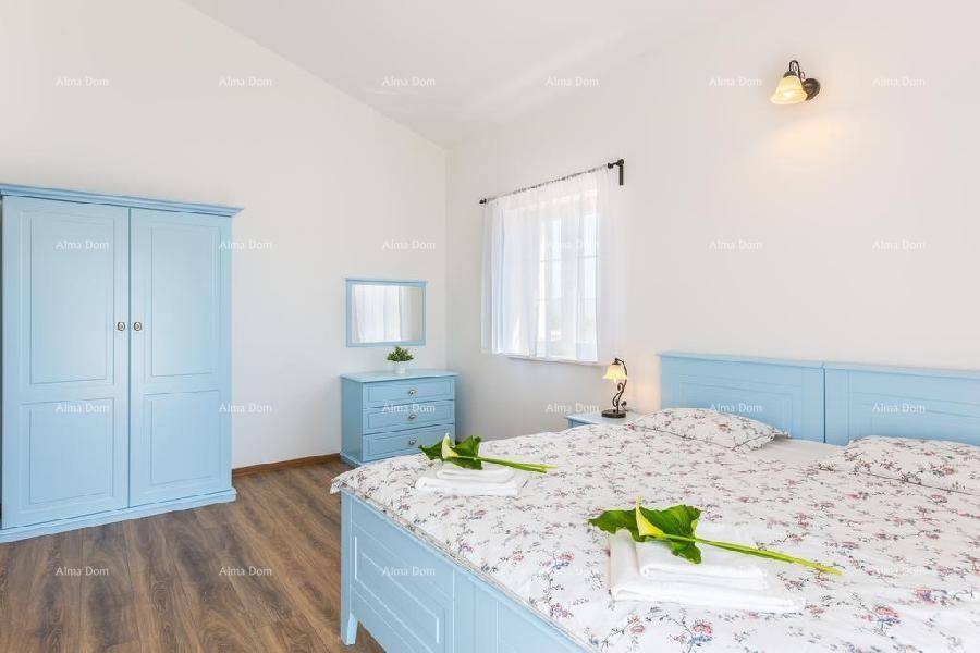 Schlafzimmer mit blauem Kleiderschrank, Kommode und Holzboden, der eine warme Atmosphäre schafft.