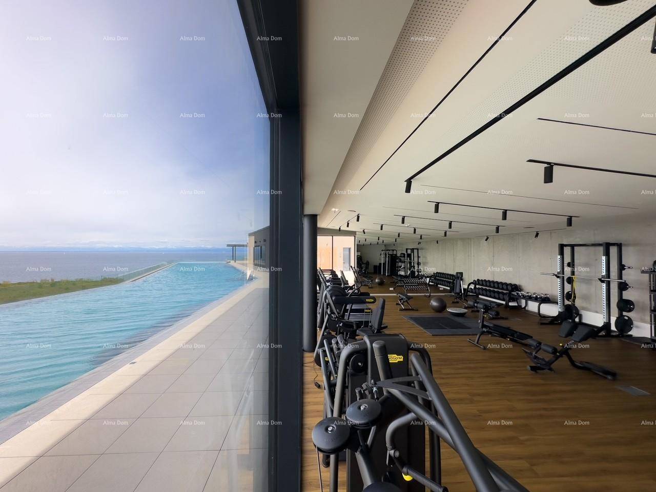 Modernes Fitnessstudio mit Meerblick und direktem Zugang zum Außenpoolbereich durch große Glasfronten.