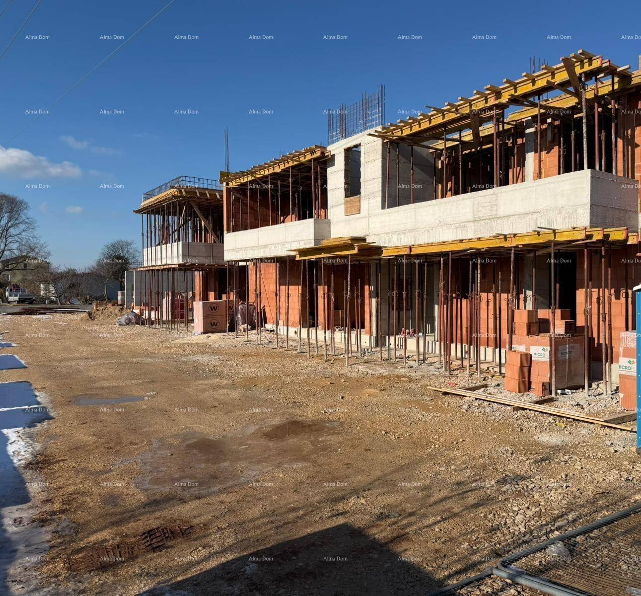 Baustelle eines neuen Wohngebäudes mit sichtbaren Ziegelwänden und Betonstrukturen unter blauem Himmel.