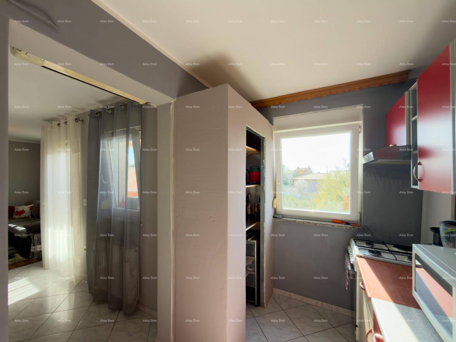 Helle Küche mit roten Schränken, Fenster und offenem Übergang zum Wohnbereich.