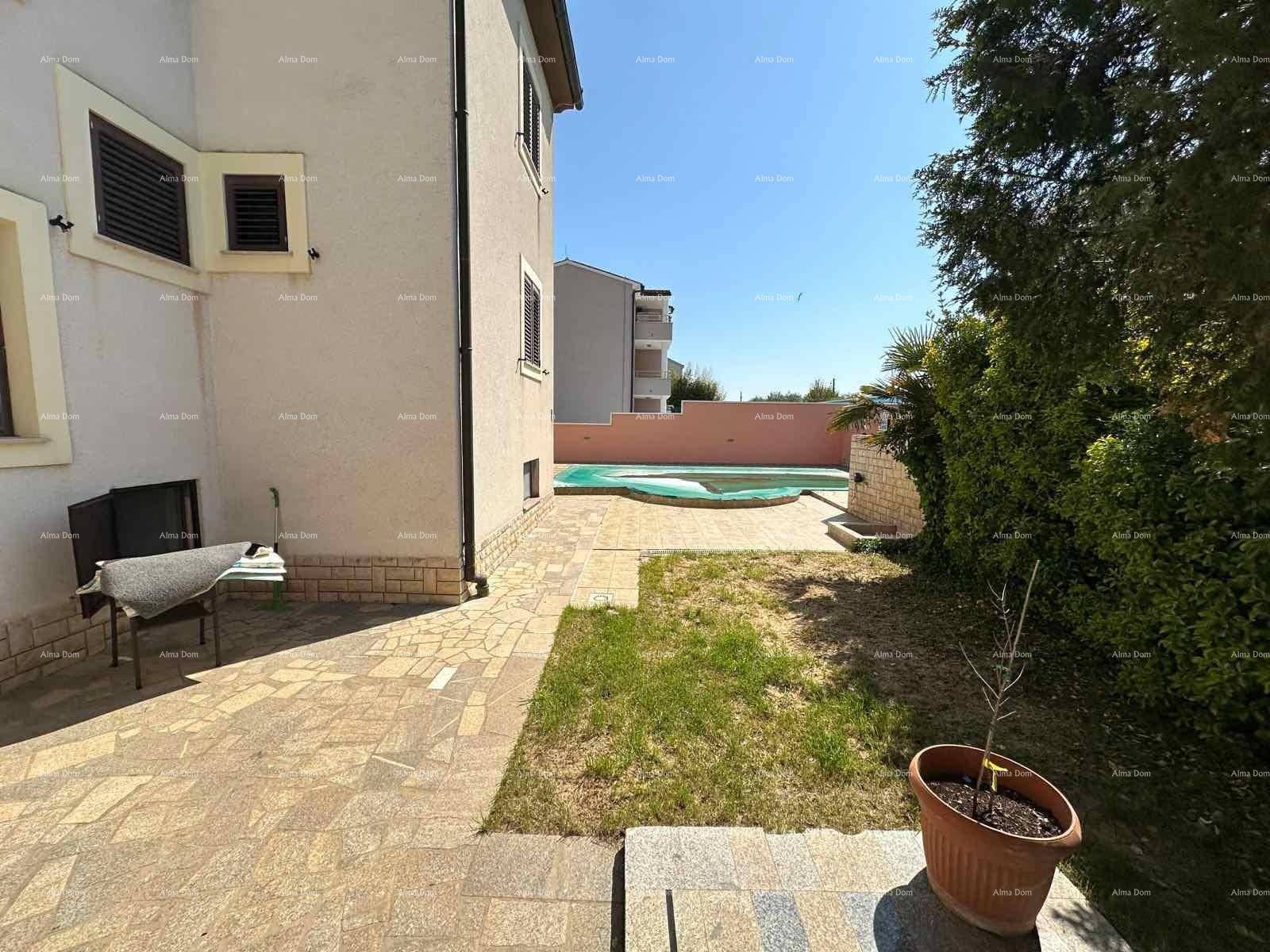 Gepflasterter Gartenbereich mit Rasenfläche und einem privaten Pool im Hintergrund.