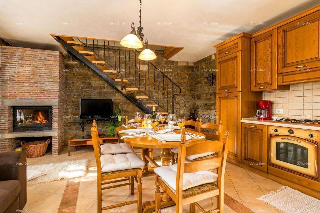 Rustikaler Wohn-Essbereich mit Steinfliesen, Holzküche, Kamin und offener Treppe.