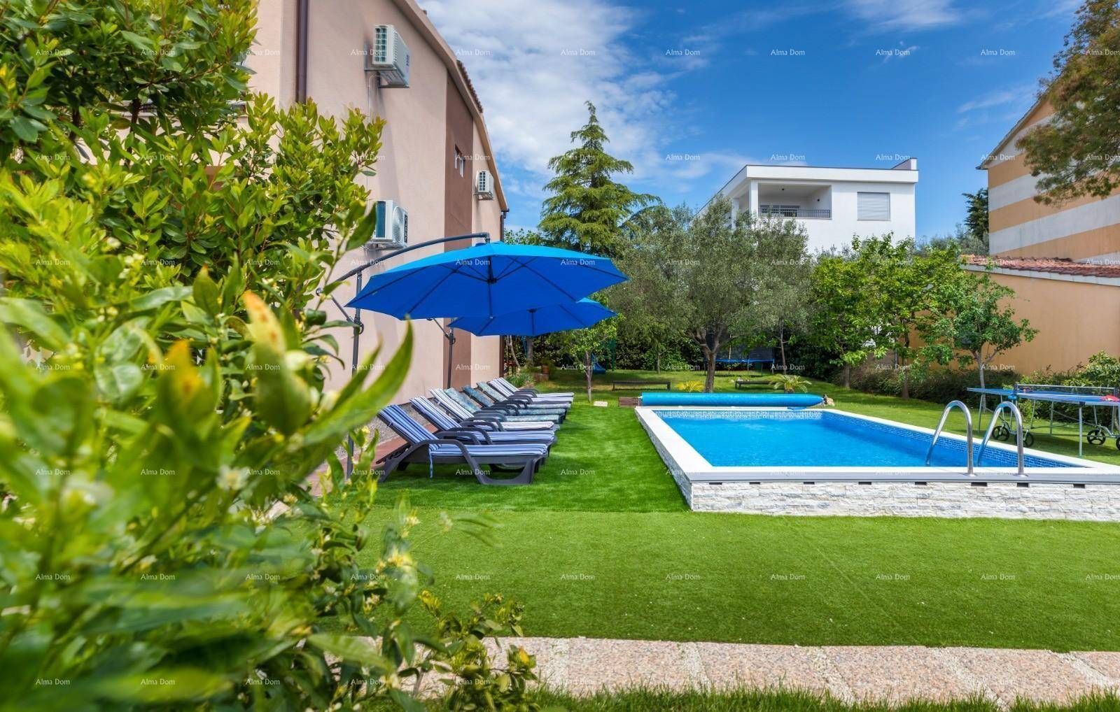 Gepflegter Gartenbereich mit Pool, Liegestühlen und Sonnenschirmen unter blauem Himmel.