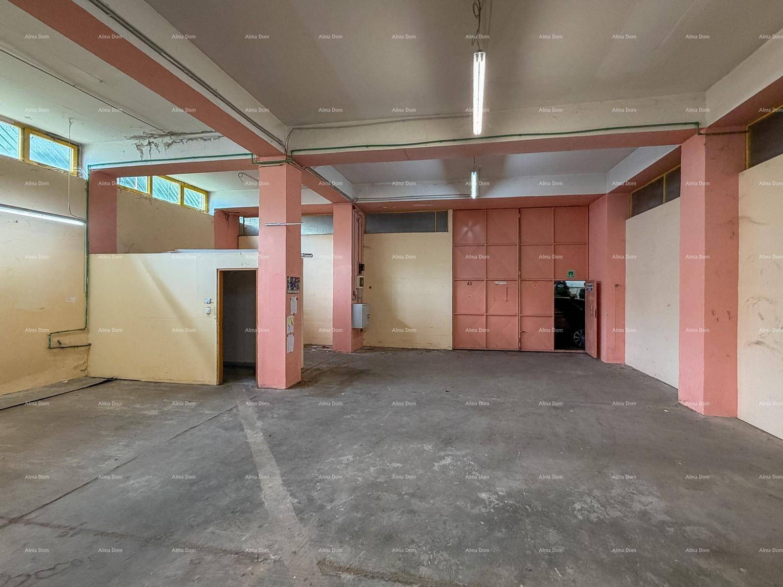 Innenansicht eines Lagerraums mit Betonboden, rosa Stützpfeilern und abgetrennten Bereichen, beleuchtet durch Oberlichter.