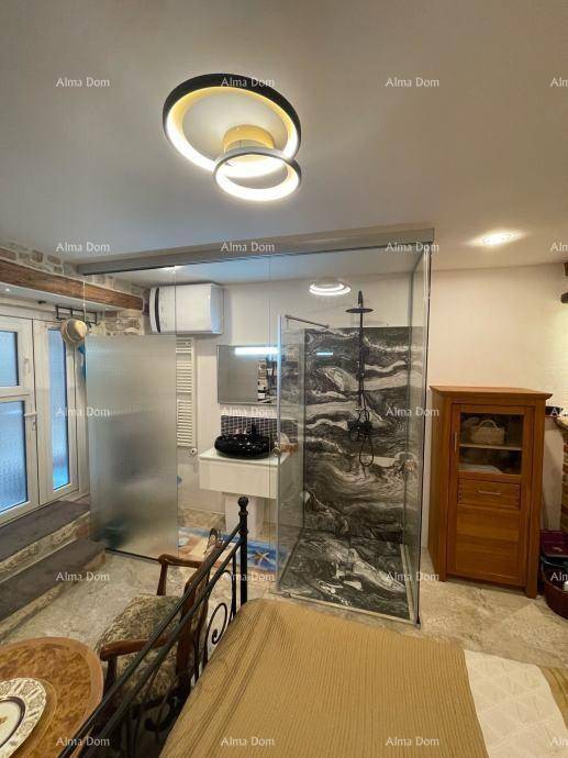 Schlafzimmer mit integriertem, modernem Badbereich, großer Glasdusche und zeitgemäßer Deckenleuchte.