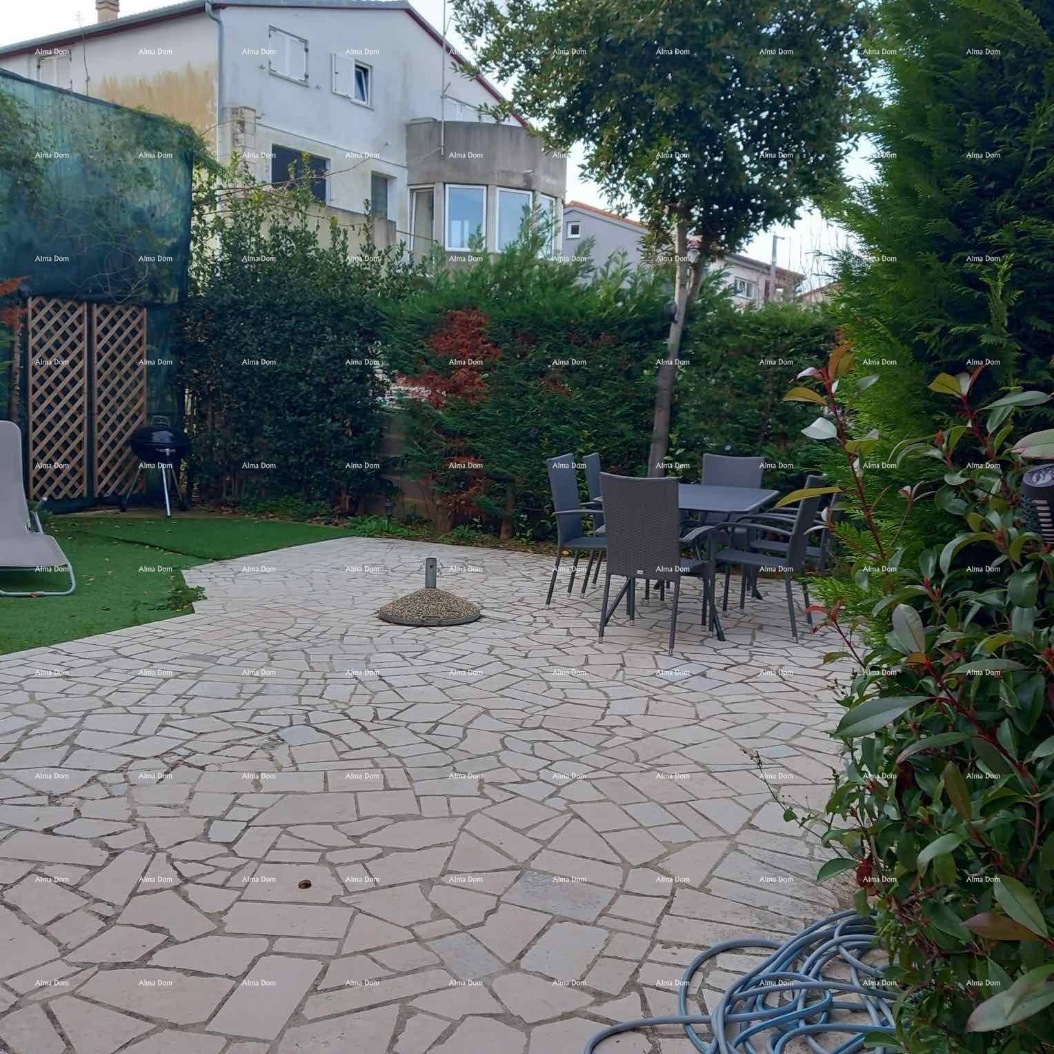 Geräumige gepflasterte Terrasse mit Esstisch und Stühlen, umgeben von grünen Hecken.