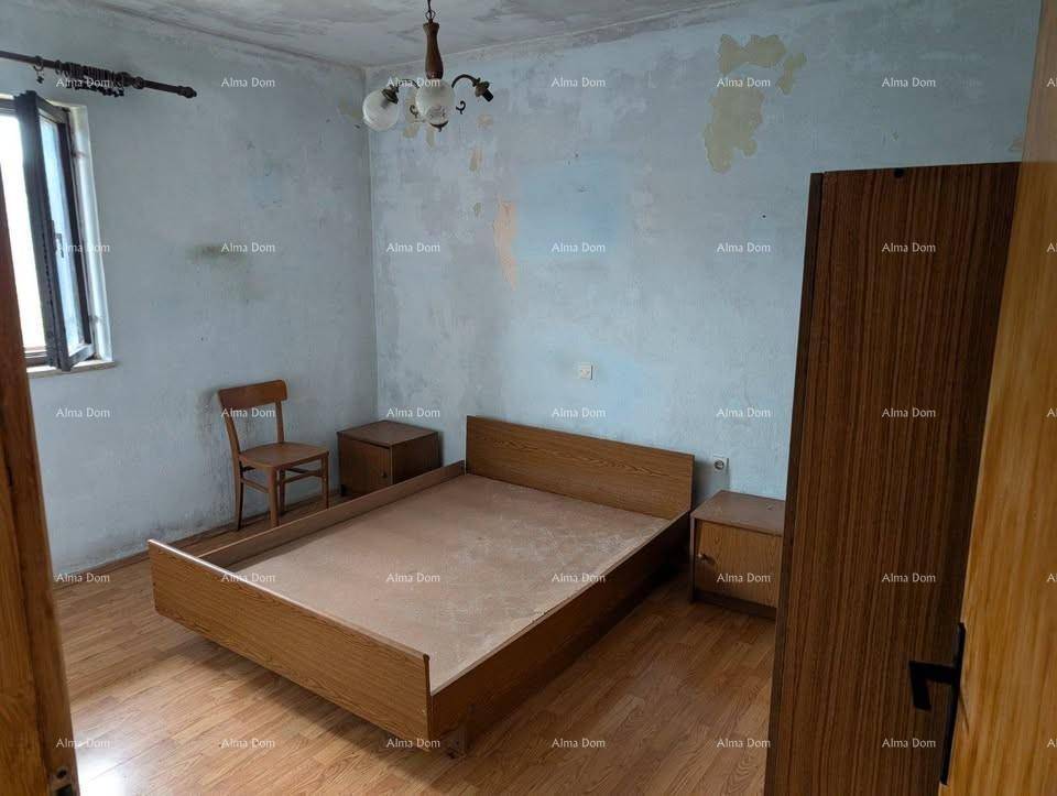 Schlafzimmer mit einfachem Holzbett und Nachttischen, Holzboden und abgenutzten Wänden.