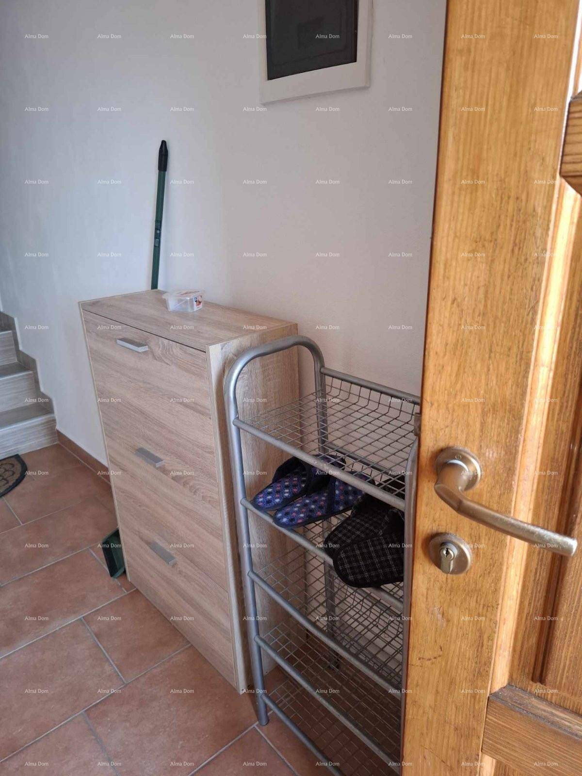 Eingangsbereich mit praktischem Schuhschrank und Ablagefläche, daneben eine Holztreppe.