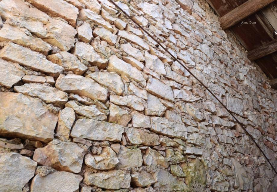 Detailansicht einer rustikalen Steinmauer mit unregelmäßigen Steinen und sichtbaren Holzbalken.