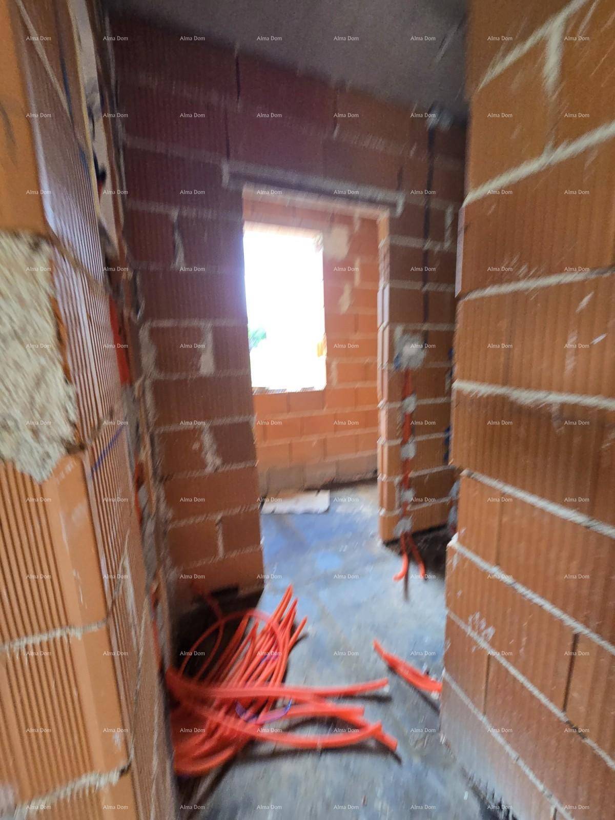 Schmaler Innenraum im Rohbau mit Ziegelwänden, Fensteröffnung und verlegten Elektroleitungen.