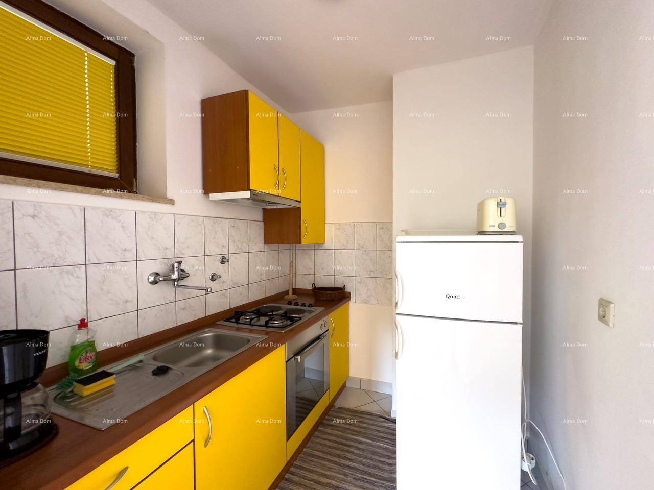 Kleine Küche mit gelben Schränken, Gasherd, Backofen und Kühlschrank, ausgestattet mit Fliesenrückwand.