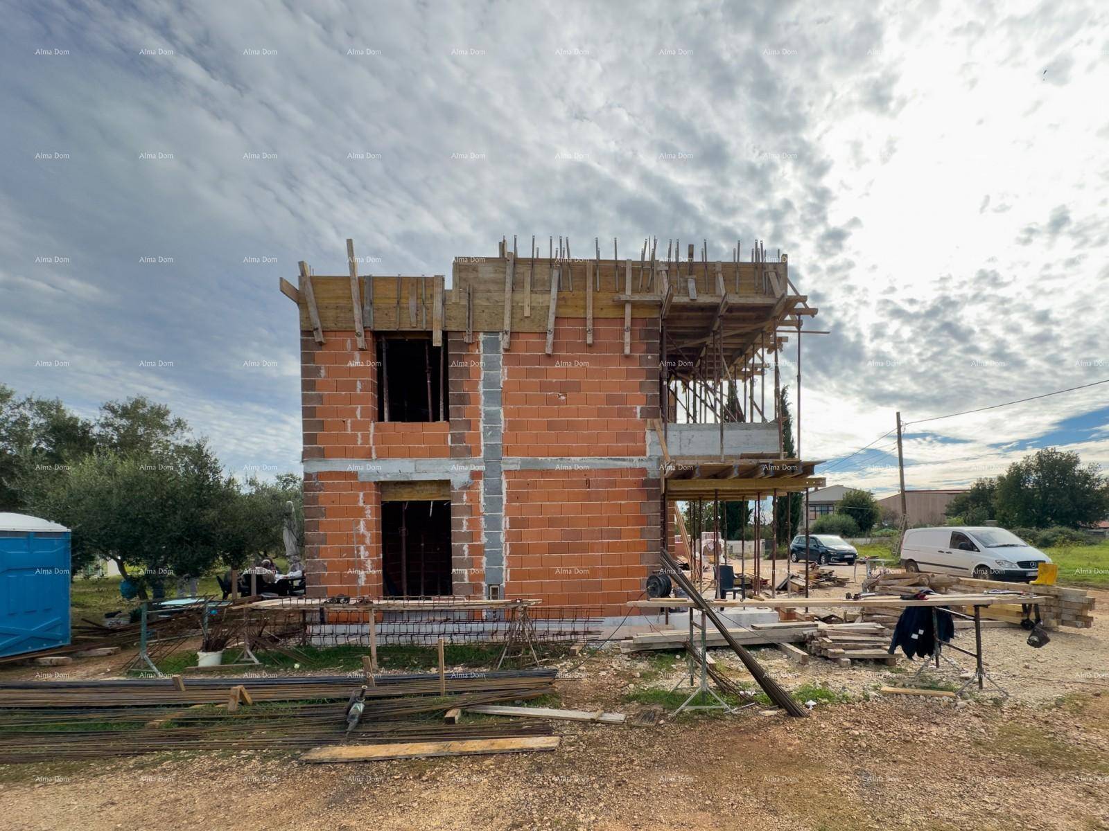 Seitenansicht des im Bau befindlichen Hauses mit unverputzten Ziegelwänden und Baugerüst.
