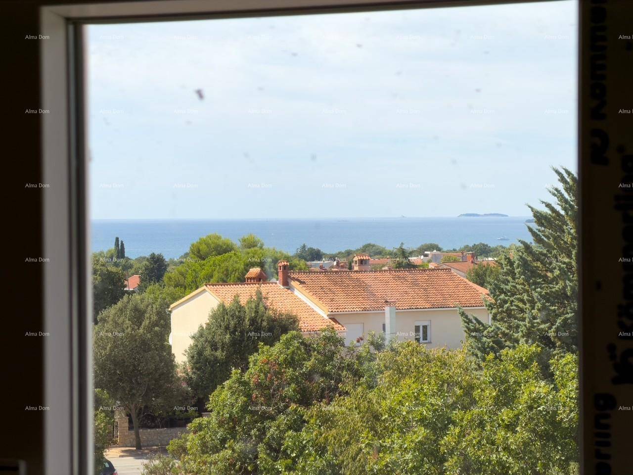Meerblick durch ein Fenster, umgeben von grünen Bäumen und roten Dächern.