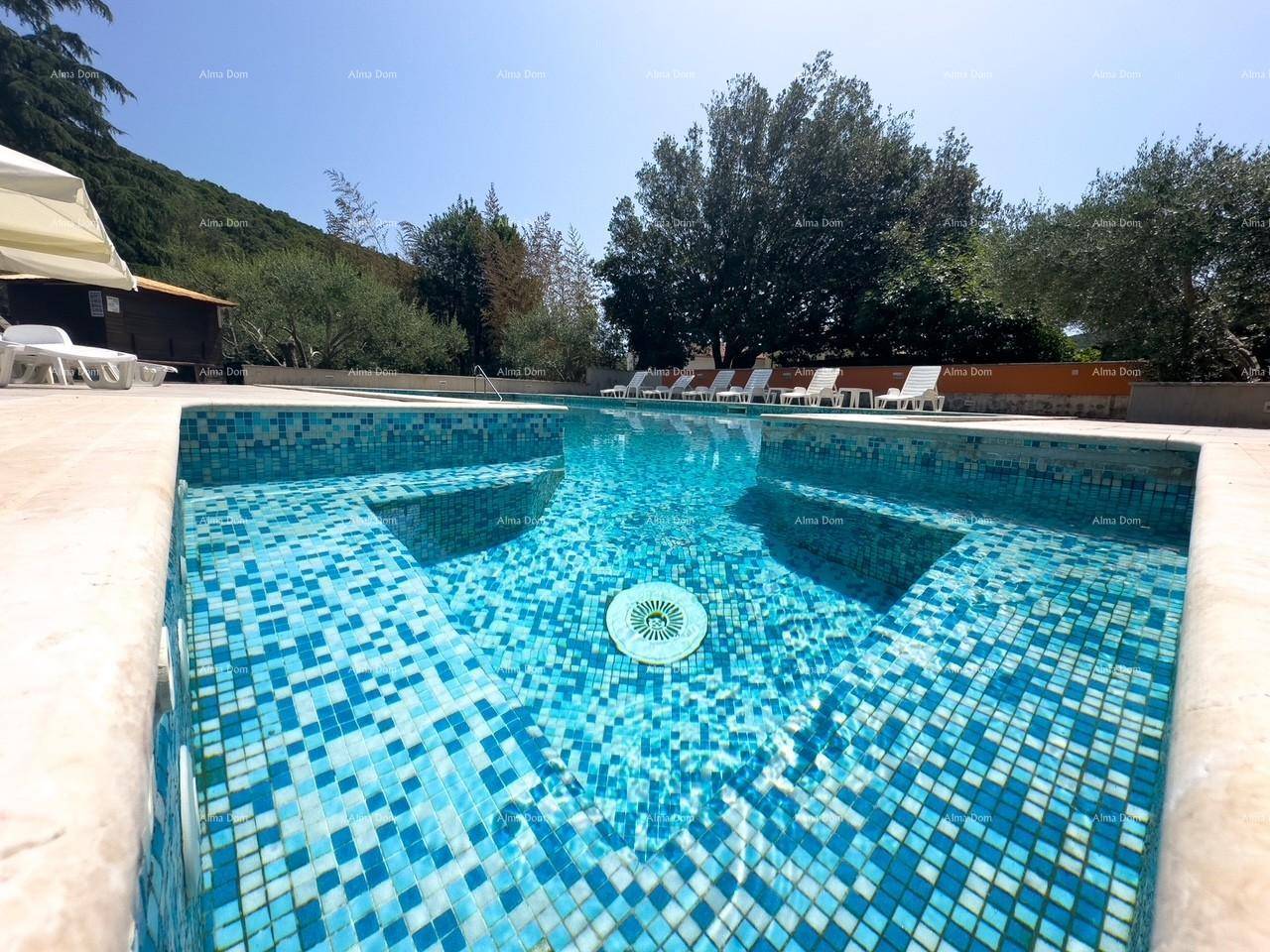 Detailansicht des Pools mit blauen Mosaikfliesen und klarem Wasser unter strahlendem Himmel.