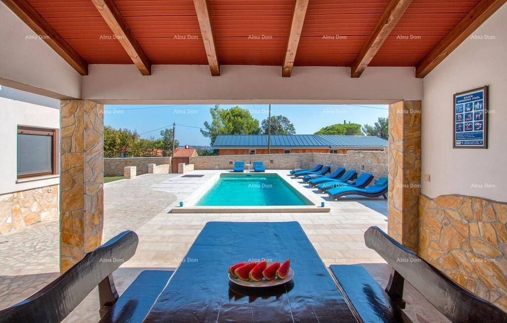 Überdachte Terrasse mit Esstisch und direktem Blick auf den erfrischenden Poolbereich.