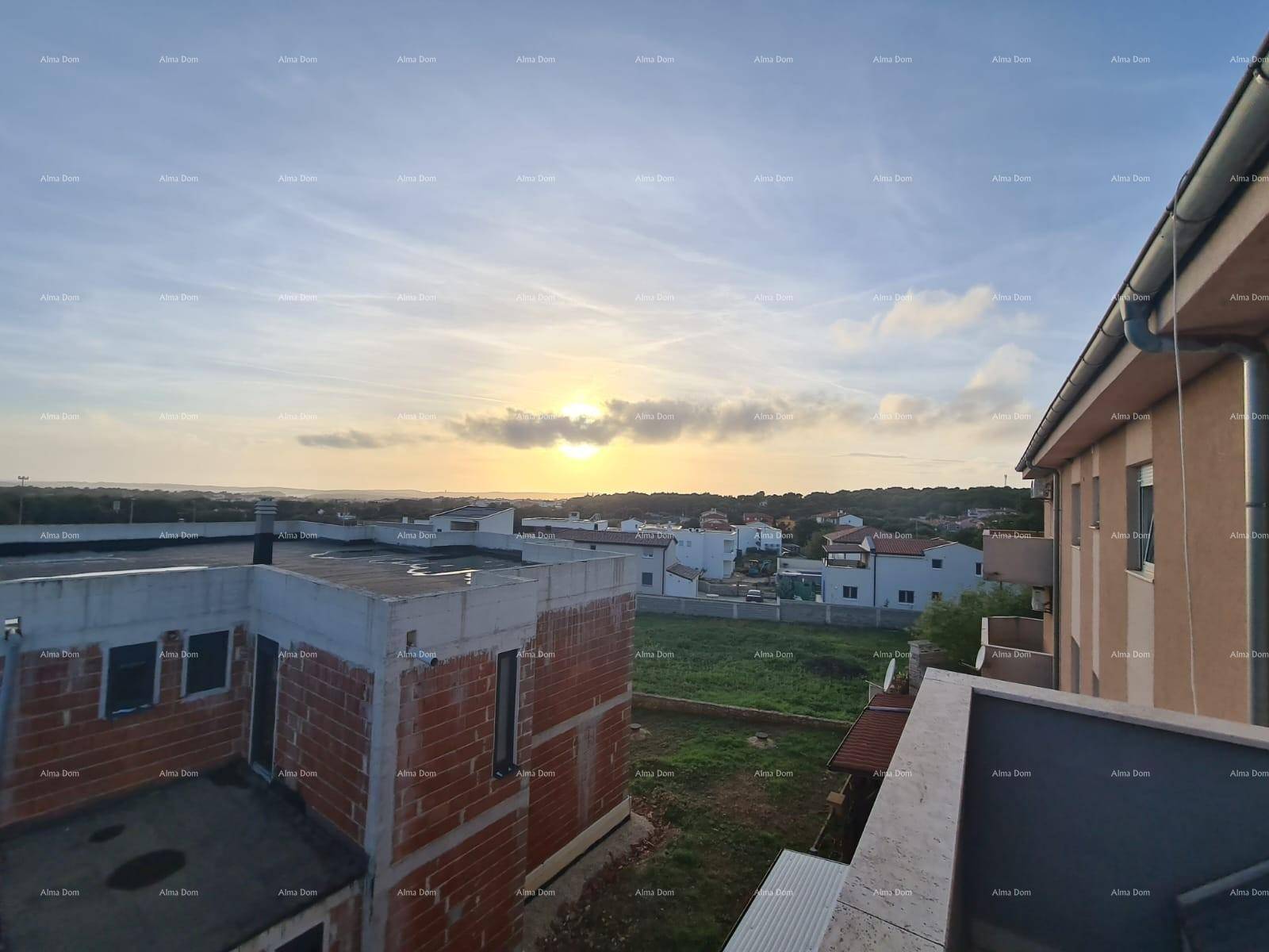 Weitläufiger Blick über die Landschaft und umliegende Gebäude bei Sonnenuntergang.