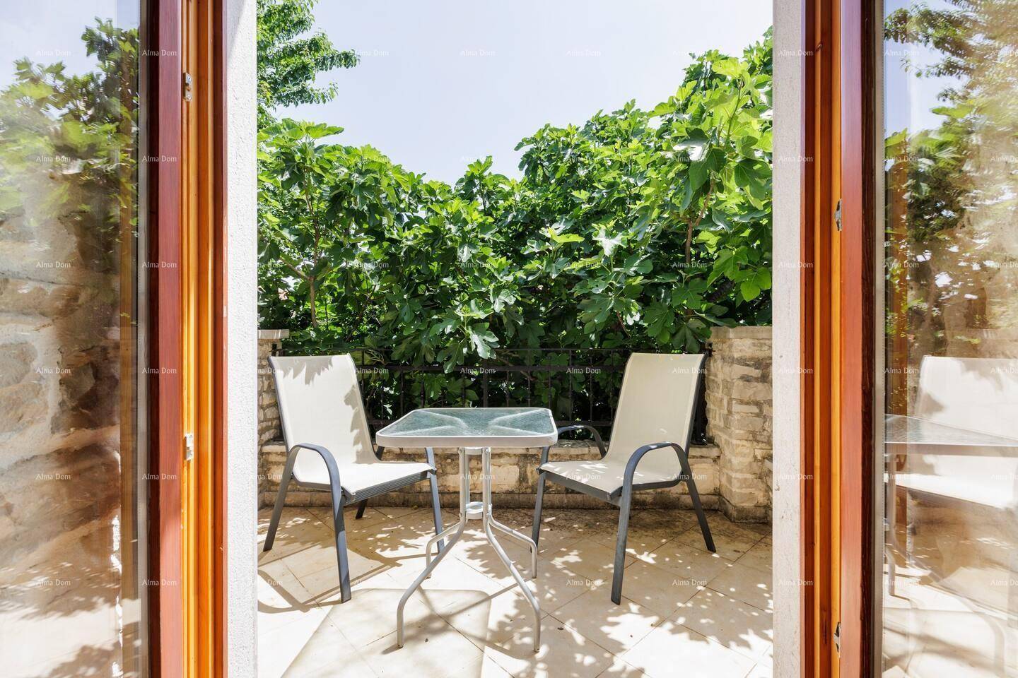 Kleiner Balkon mit Tisch und Stühlen, umgeben von dichtem Grün für Privatsphäre.