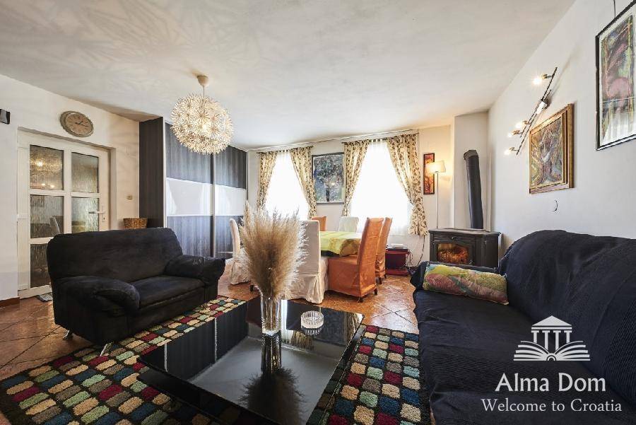 Geräumiger Wohn- und Essbereich mit bequemen Sofas, Esstisch und Kaminofen auf Fliesenboden.