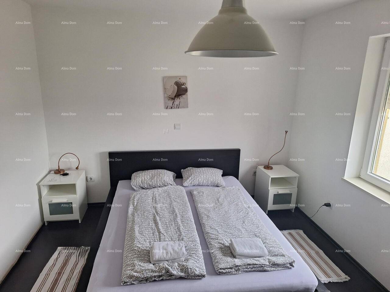 Helles Schlafzimmer mit Doppelbett, Nachttischen und einem Fenster für natürliches Licht.