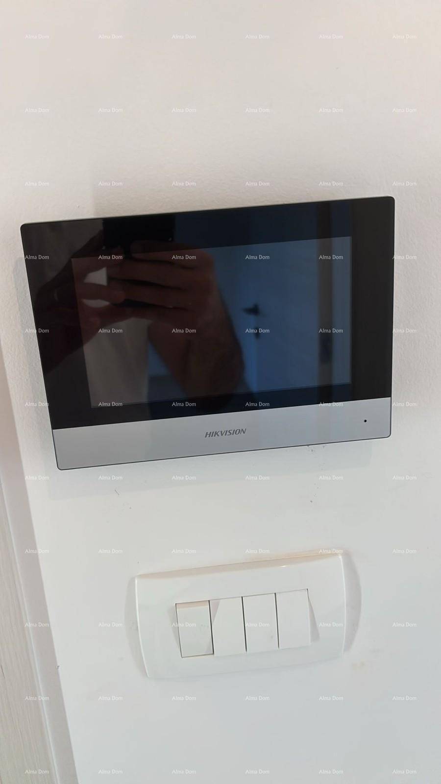 Moderne Gegensprechanlage mit Bildschirm und Lichtschaltern an einer weißen Wand.