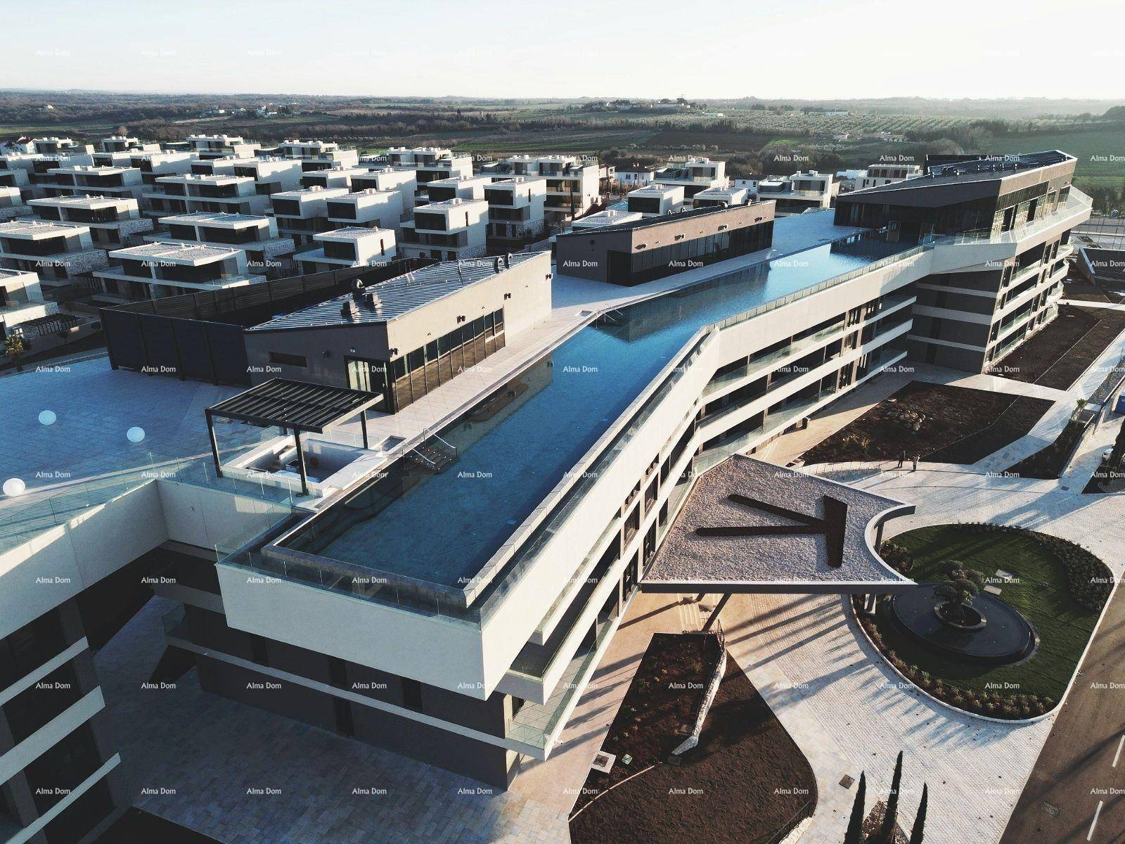 Luftaufnahme eines modernen Gebäudekomplexes mit einem beeindruckenden Infinity-Pool auf dem Dach.