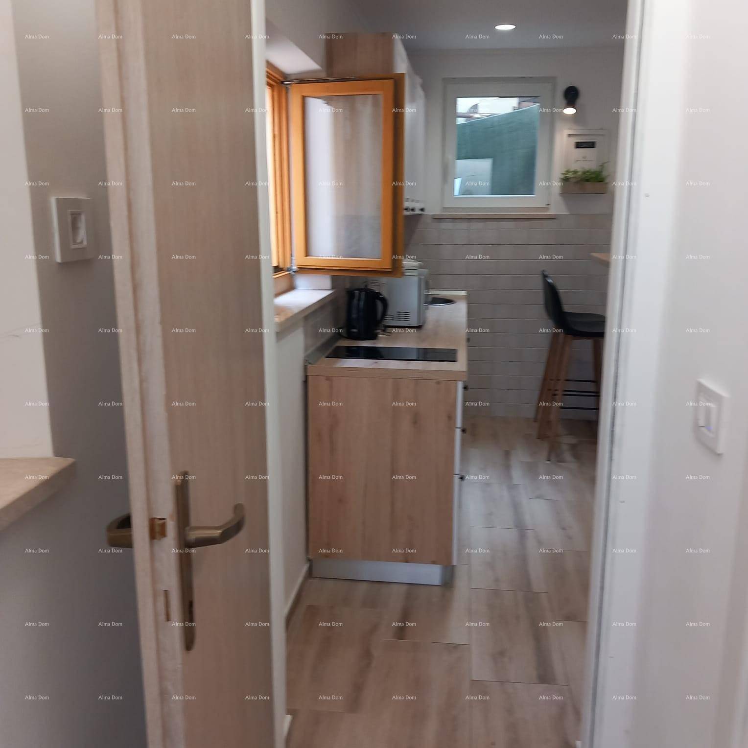 Kleine, funktionale Küchenzeile mit Holzfronten und Fenster, vom Flur aus sichtbar.
