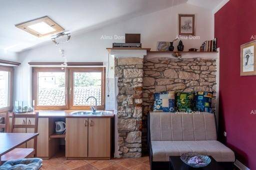 Offener Wohn- und Essbereich mit kleiner Küchenzeile, Steinwand und Dachfenster, bietet rustikalen Charme.
