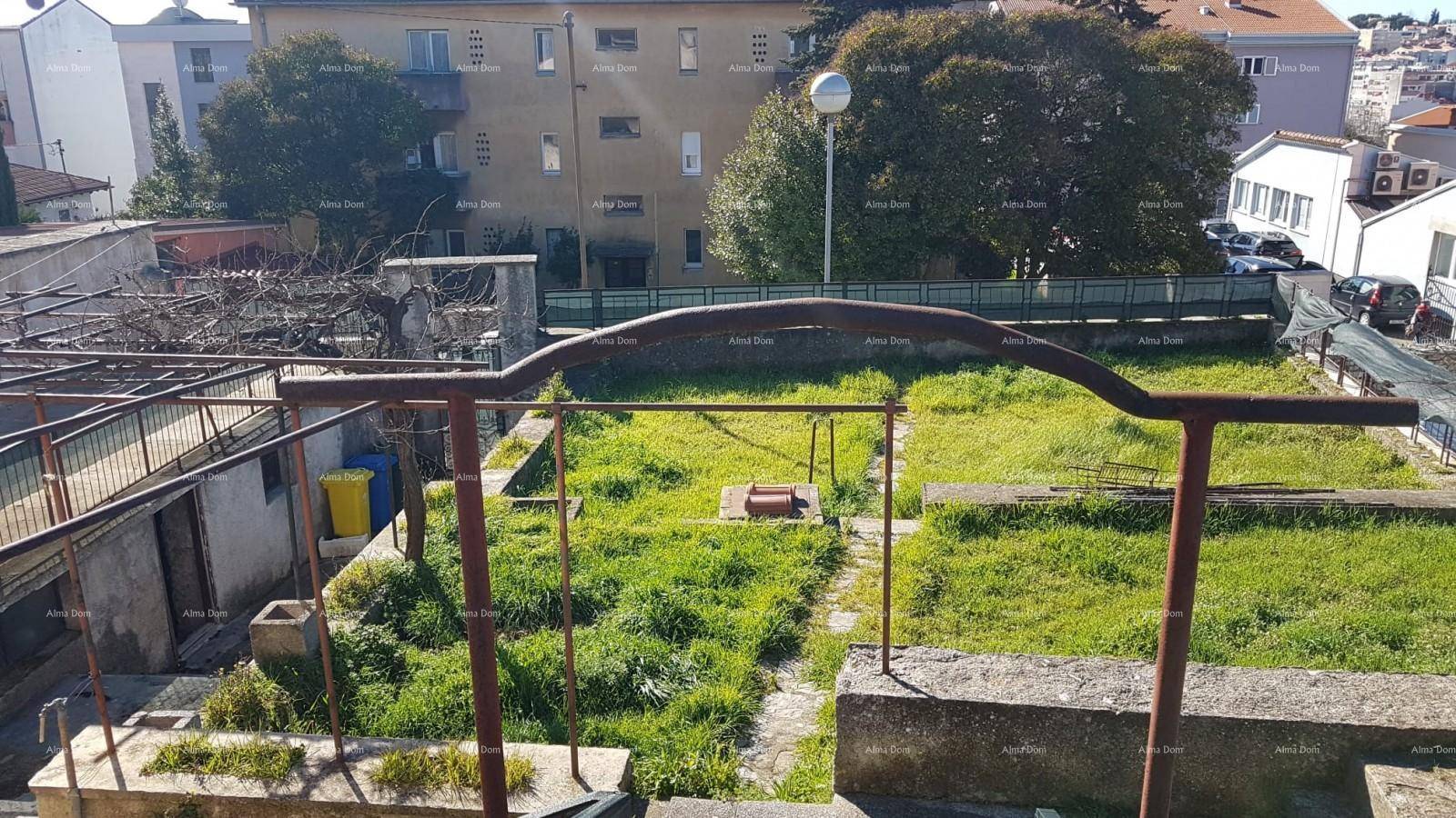 Erhöhter Blick auf den terrassierten Gartenbereich mit Rasen und umliegenden Gebäuden in der Ferne.