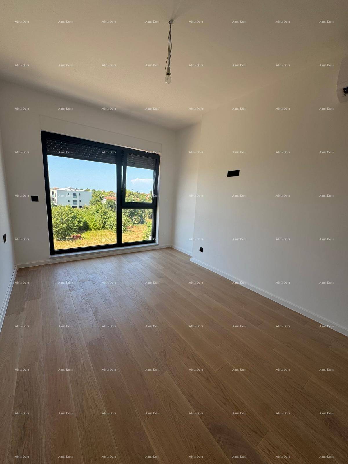 Helles Zimmer mit Holzboden, großen Fenstern und Blick auf die Umgebung.