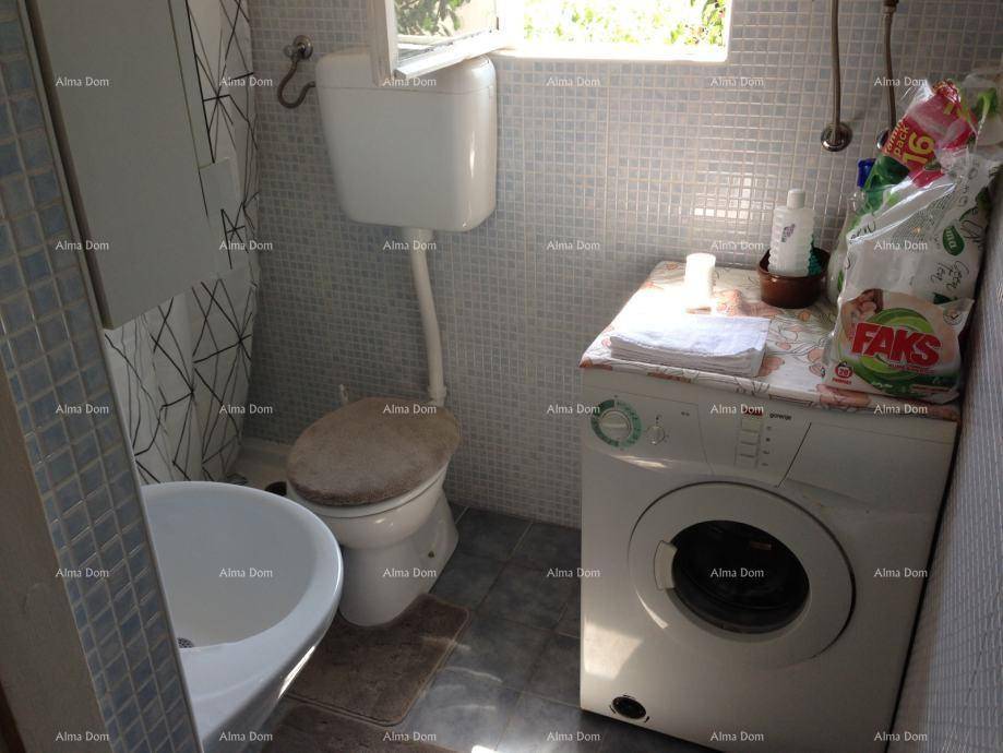 Kleines WC mit Waschmaschine und Fenster.