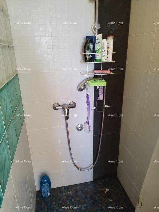 Duschbereich im Badezimmer mit weißen und türkisfarbenen Fliesen sowie einer einfachen Duscharmatur.
