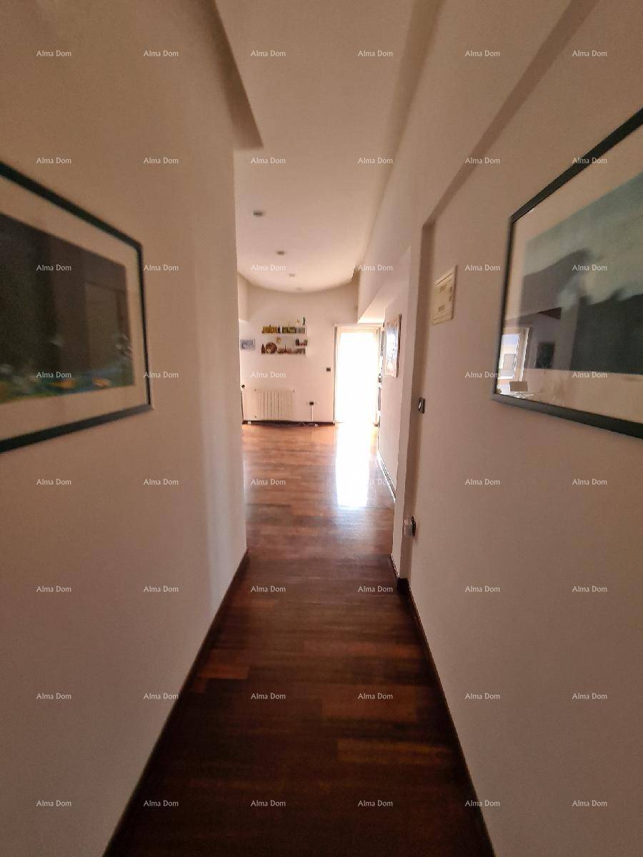 Langer, heller Flur mit dunklem Holzboden und Kunstwerken an den Wänden.