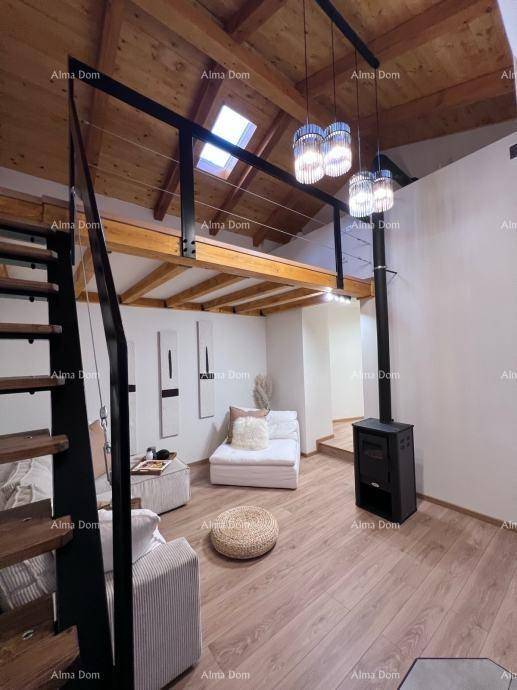 Hoher Wohnbereich mit Holzbalken, Kaminofen und offener Galerie mit Dachfenster, schafft ein Loft-Gefühl.