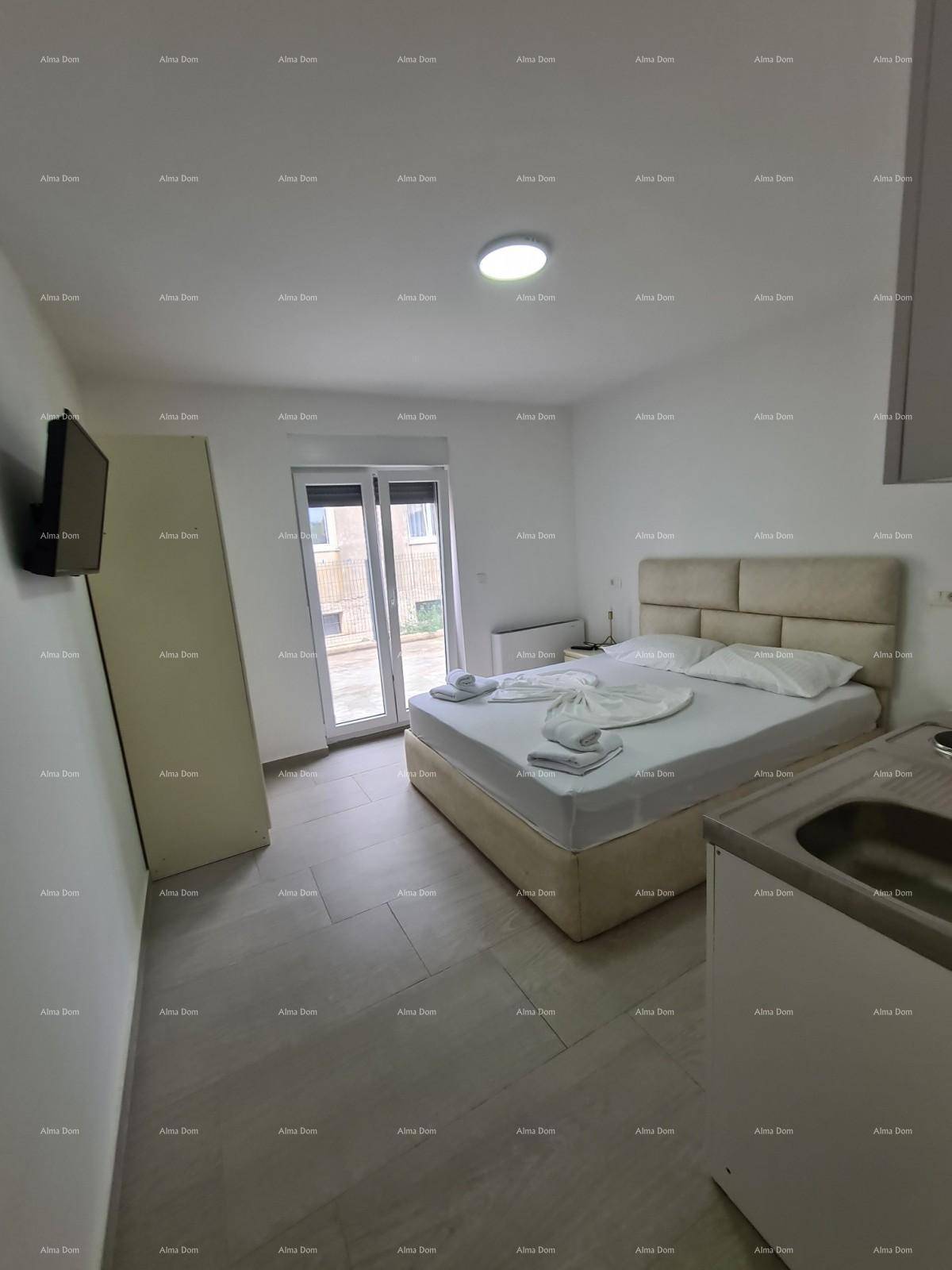 Helles Schlafzimmer mit Doppelbett, Kleiderschrank und kleiner Küchenzeile.