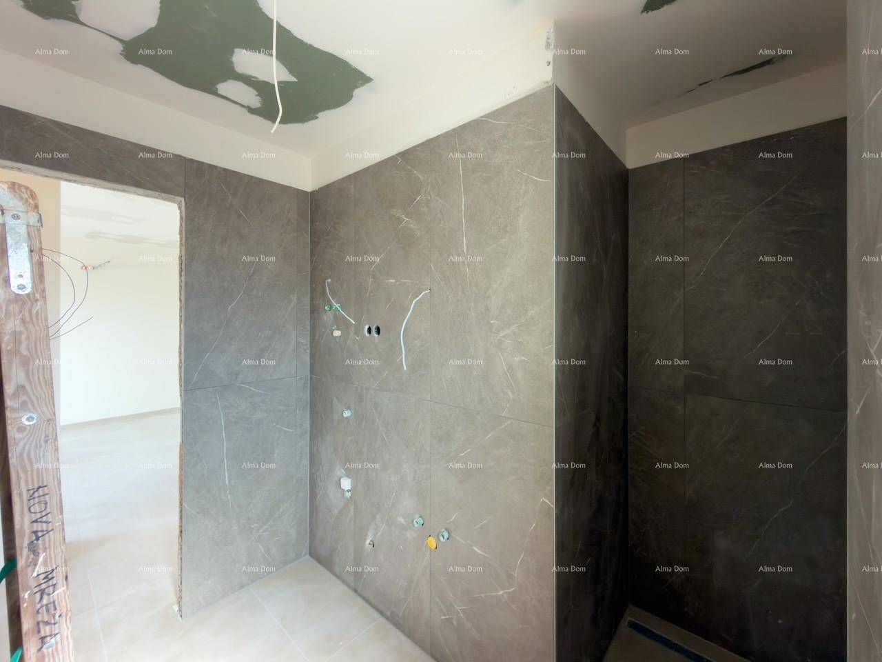 Unfertiges Badezimmer mit grauen Fliesenwänden und sichtbaren Elektroinstallationen.