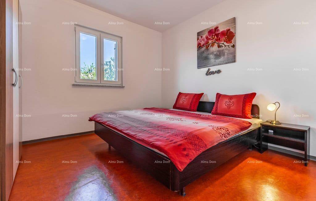 Helles Schlafzimmer mit roter Bettwäsche, Doppelbett und Fenster für angenehmes Licht.