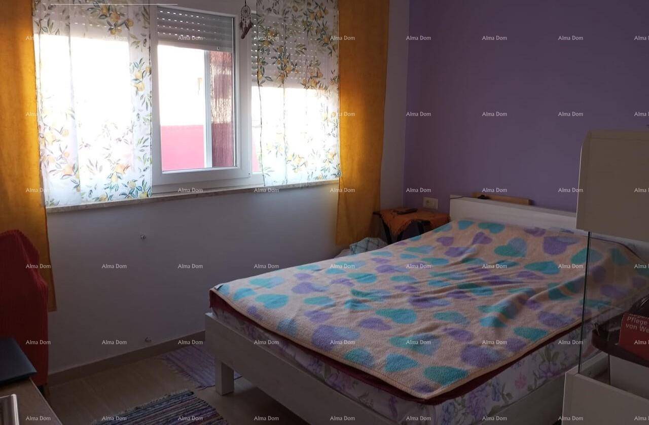 Schlafzimmer mit lila Wänden, einem Bett und einem Fenster mit bunten Vorhängen.